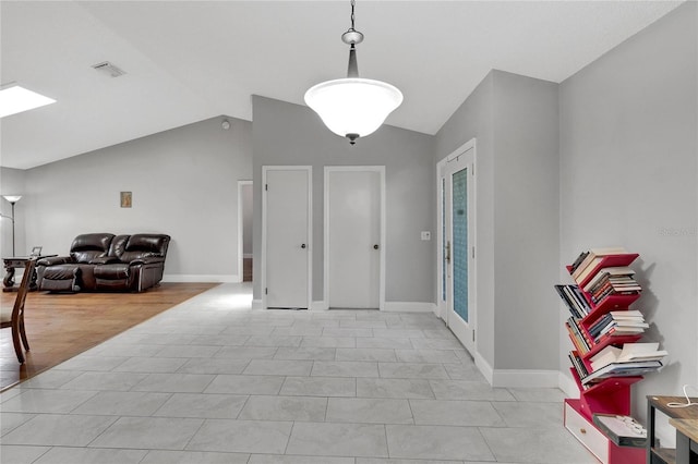 foyer entrance featuring visible vents, vaulted ceiling, light wood finished floors, and baseboards