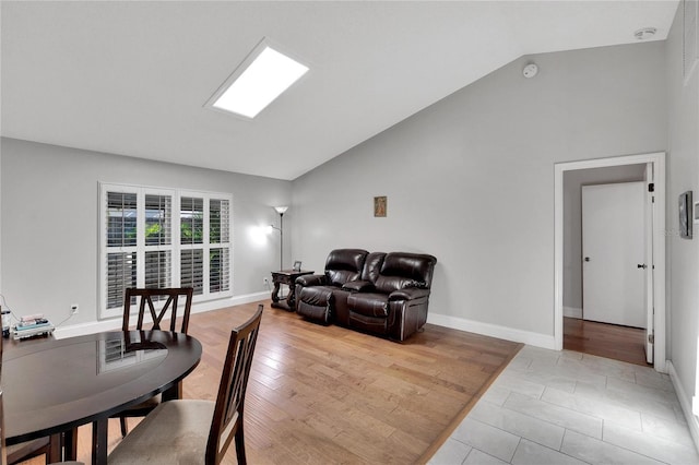 living room featuring light wood-style floors, high vaulted ceiling, and baseboards