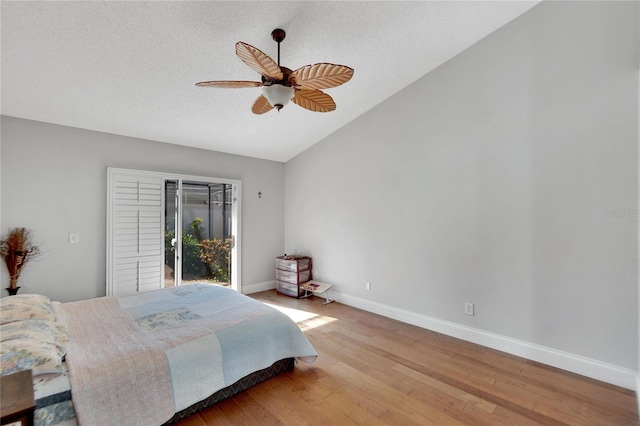 bedroom with a textured ceiling, a ceiling fan, baseboards, vaulted ceiling, and light wood-style floors