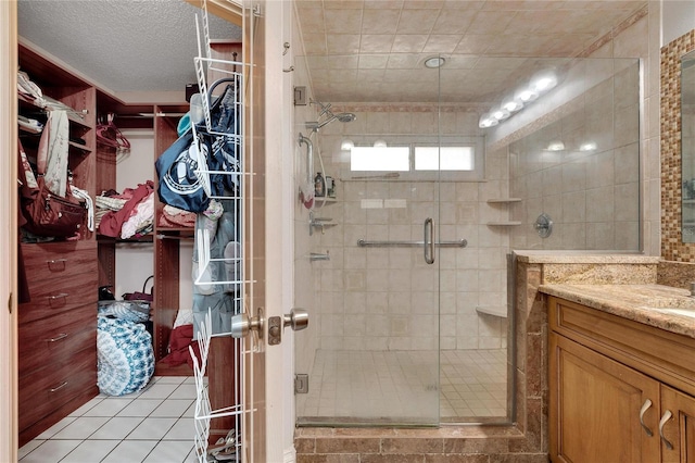 bathroom with a stall shower, a walk in closet, vanity, and tile patterned floors