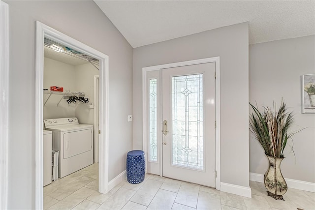 entrance foyer featuring a textured ceiling, separate washer and dryer, light tile patterned floors, and baseboards