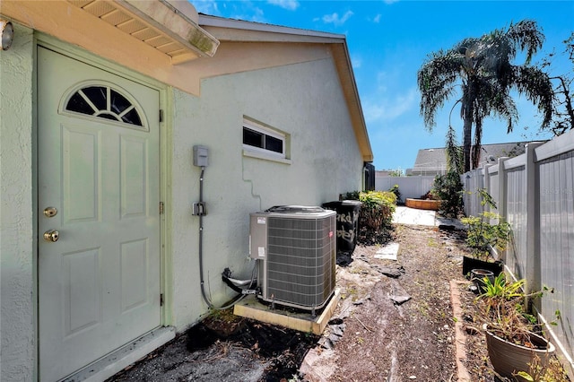 exterior space with fence, central AC unit, and stucco siding