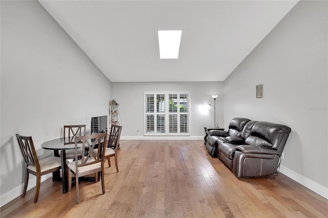 dining space with vaulted ceiling, light wood finished floors, and baseboards