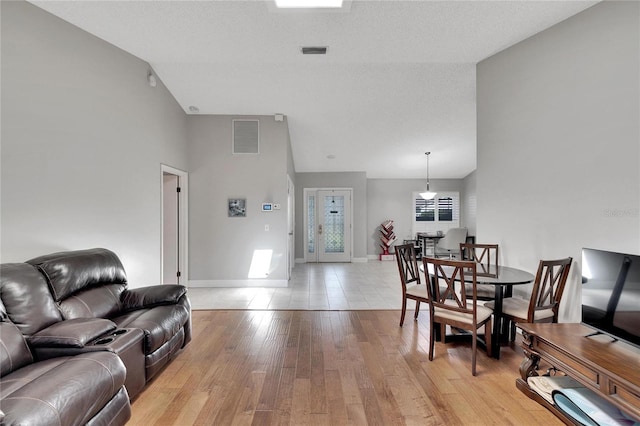 living room with light wood-style flooring, visible vents, and baseboards