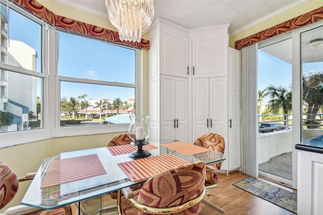 dining room with light wood-type flooring, ornamental molding, and an inviting chandelier