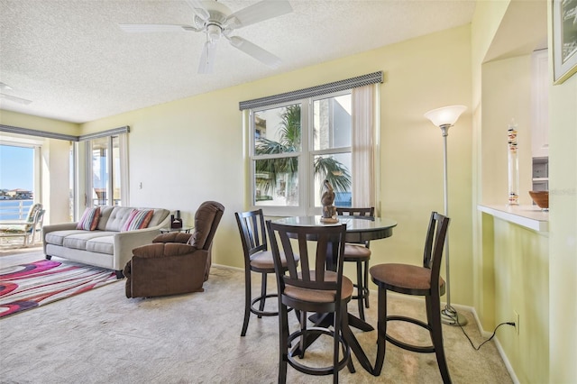 living room with light carpet, ceiling fan, and a textured ceiling