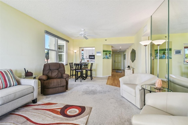 living room featuring a textured ceiling, light colored carpet, and ceiling fan