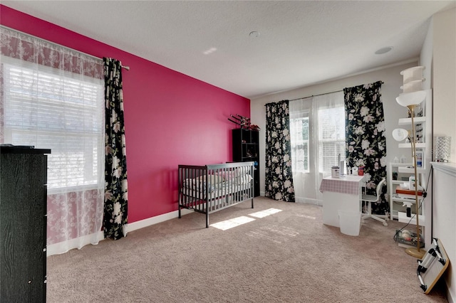 bedroom with carpet flooring, a nursery area, and a textured ceiling