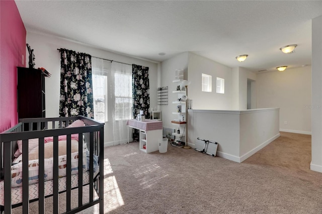 carpeted bedroom with a crib and a textured ceiling