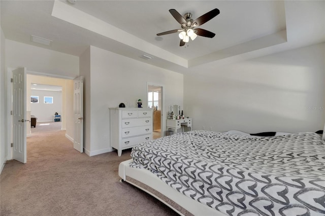 bedroom with a raised ceiling, ceiling fan, and light colored carpet