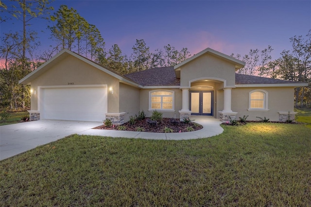 view of front facade featuring french doors, a yard, and a garage