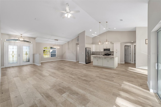 unfurnished living room featuring french doors, sink, vaulted ceiling, ceiling fan, and light wood-type flooring