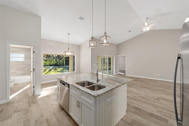 kitchen with sink, stainless steel appliances, light hardwood / wood-style flooring, decorative light fixtures, and a kitchen island with sink