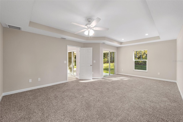 spare room featuring a tray ceiling, ceiling fan, and carpet floors