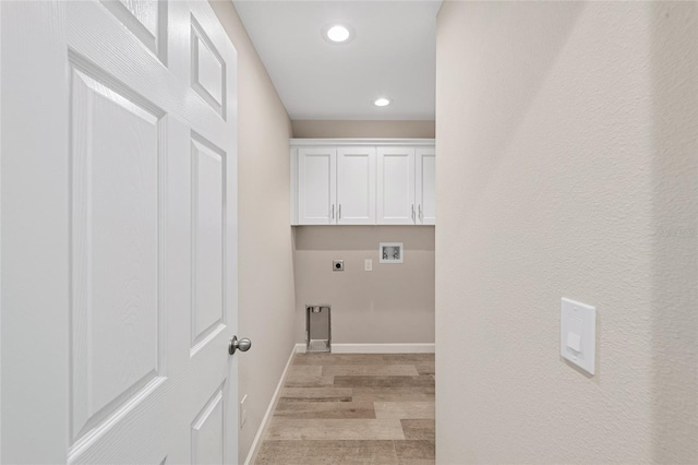 clothes washing area featuring hookup for an electric dryer, washer hookup, light hardwood / wood-style flooring, and cabinets