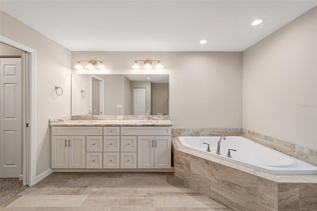 bathroom with tiled tub and vanity