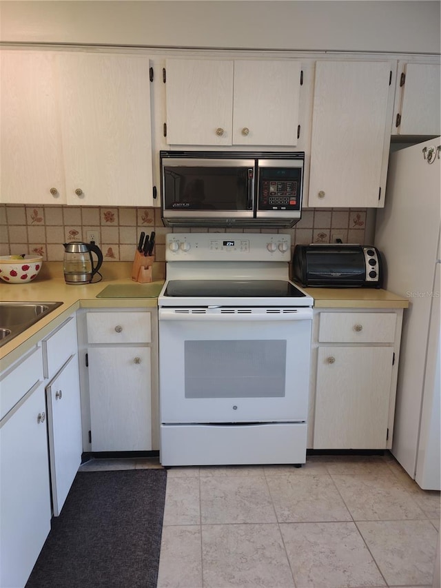 kitchen featuring tasteful backsplash, sink, light tile patterned floors, and white appliances