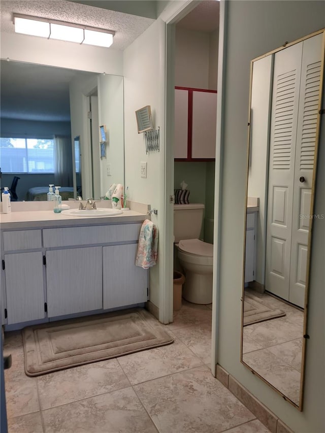 bathroom with vanity, toilet, and a textured ceiling