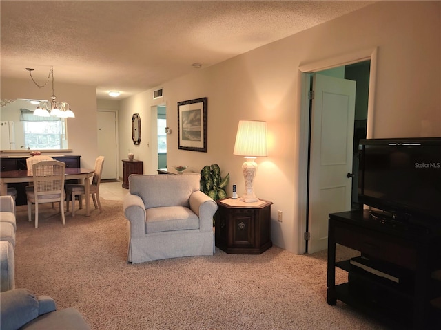 living room featuring light carpet, a textured ceiling, and a chandelier