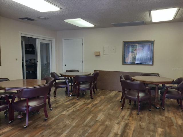 dining area with a textured ceiling and dark hardwood / wood-style flooring