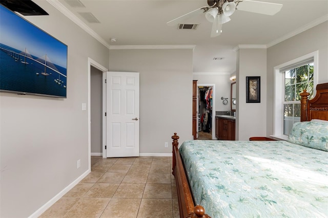 tiled bedroom featuring a walk in closet, ensuite bath, ceiling fan, crown molding, and a closet