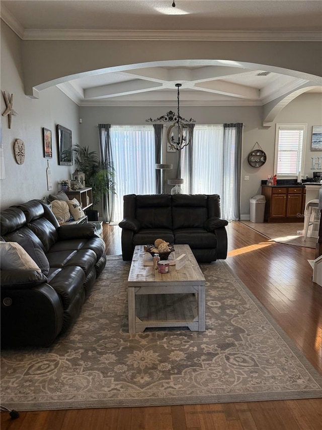 living room featuring crown molding, dark wood-type flooring, and a notable chandelier