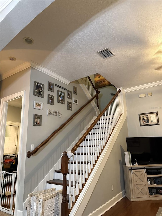 stairs featuring crown molding, wood-type flooring, and a textured ceiling