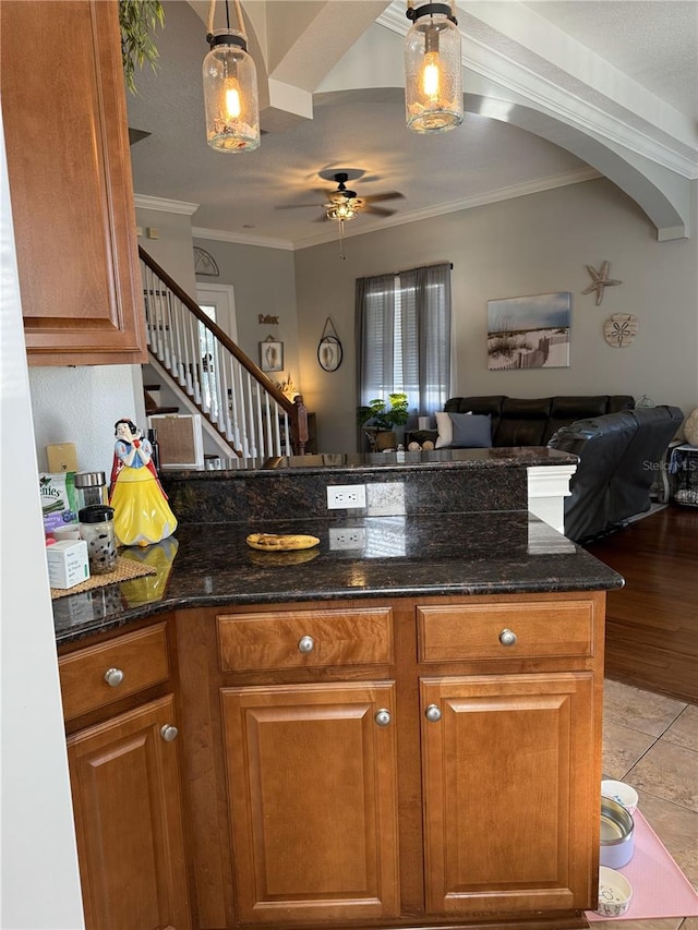 kitchen with crown molding, hanging light fixtures, and dark stone countertops