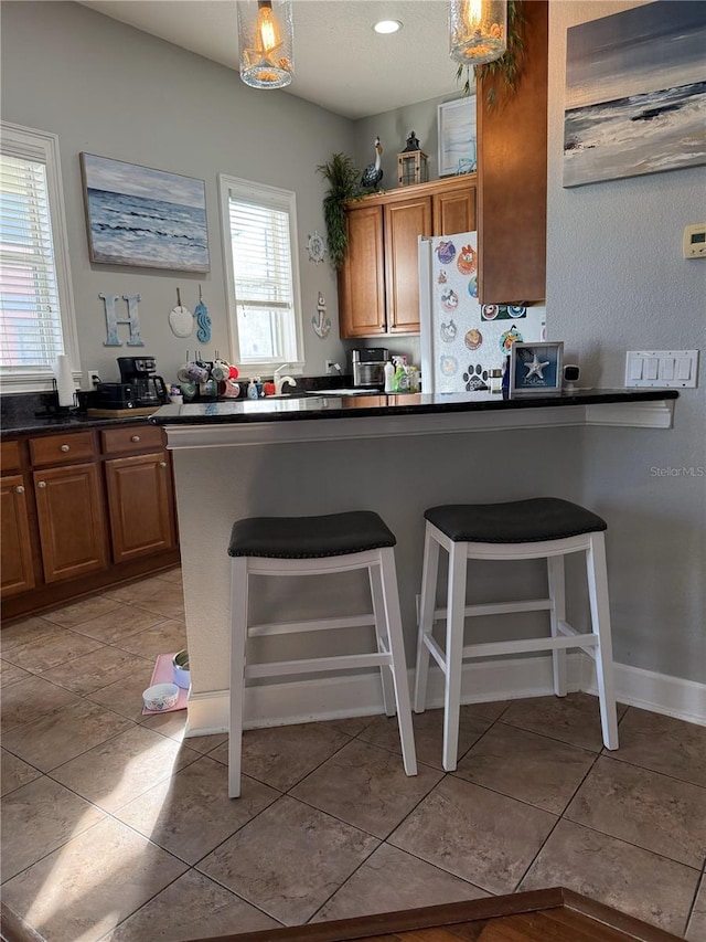 kitchen featuring light tile patterned flooring, a kitchen bar, and hanging light fixtures