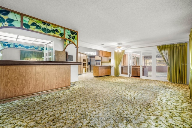 kitchen featuring kitchen peninsula, light colored carpet, and a textured ceiling