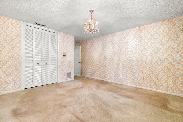 unfurnished bedroom featuring a closet, carpet, a textured ceiling, and an inviting chandelier