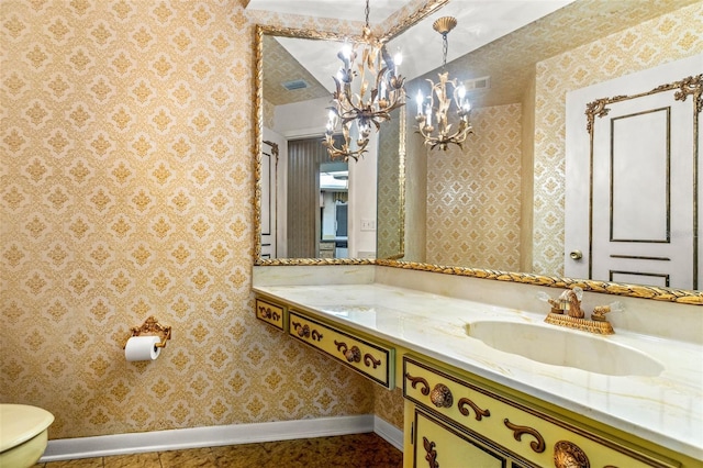 bathroom with vanity, toilet, and a chandelier