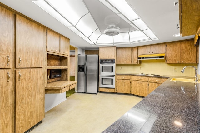 kitchen with decorative backsplash, appliances with stainless steel finishes, and sink