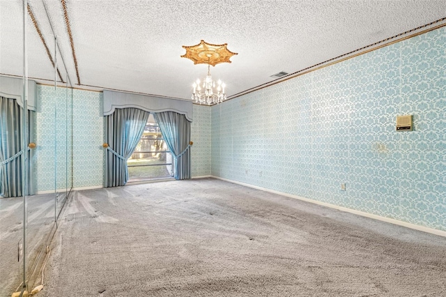 carpeted spare room with a textured ceiling and a notable chandelier