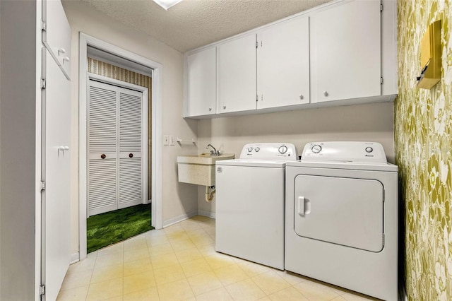 washroom with washer and clothes dryer, cabinets, sink, and a textured ceiling