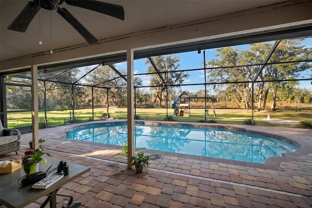 view of swimming pool featuring glass enclosure, ceiling fan, and a patio