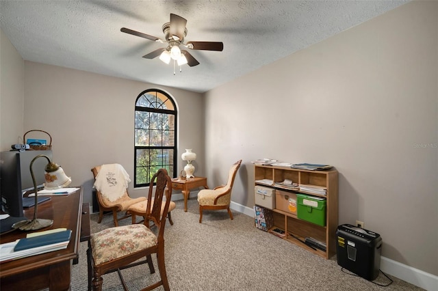 carpeted home office featuring a textured ceiling and ceiling fan