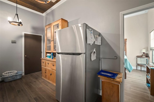 kitchen with stainless steel fridge, dark hardwood / wood-style flooring, ornamental molding, an inviting chandelier, and hanging light fixtures