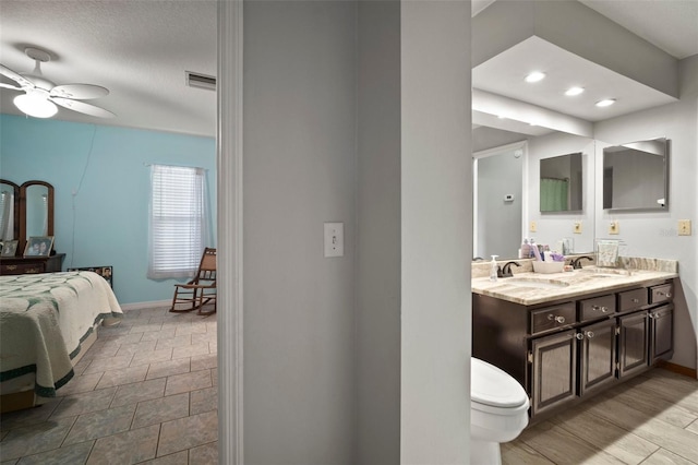 bathroom with vanity, ceiling fan, and a textured ceiling