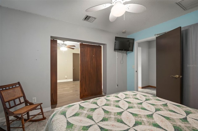 bedroom with ceiling fan, light hardwood / wood-style floors, and a textured ceiling