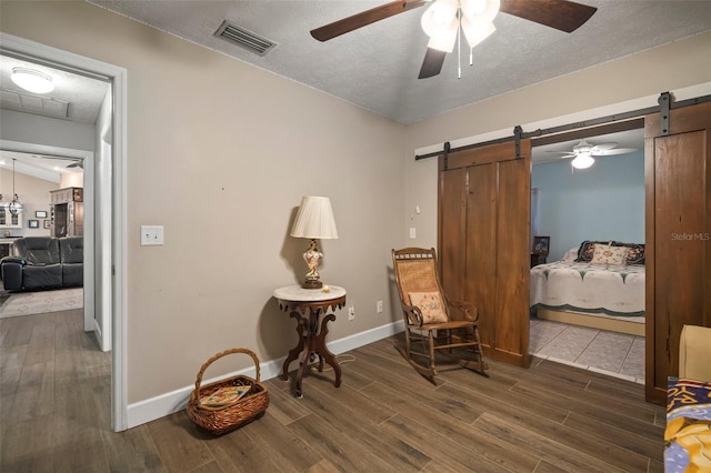 living area with a barn door, dark wood-type flooring, and a textured ceiling