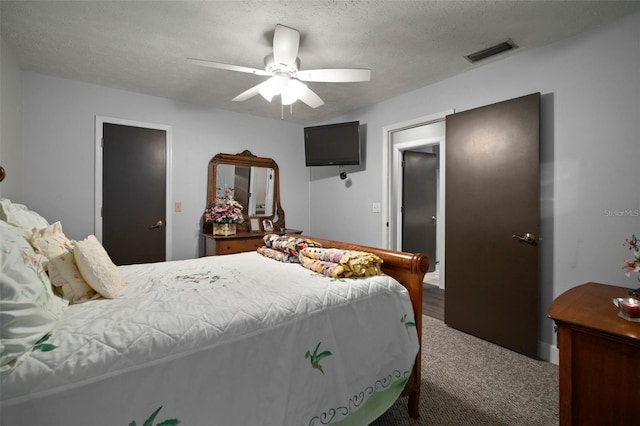 bedroom with ceiling fan, carpet floors, and a textured ceiling