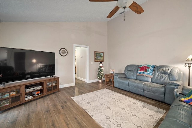 living room with ceiling fan, dark wood-type flooring, and high vaulted ceiling