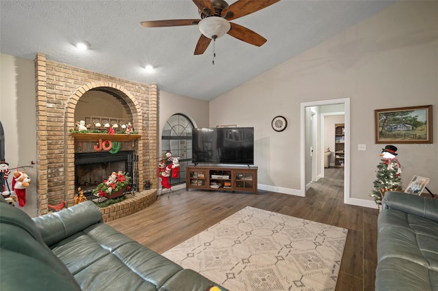 living room with a textured ceiling, ceiling fan, dark wood-type flooring, high vaulted ceiling, and a fireplace