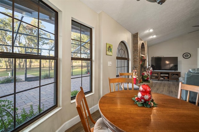 dining room with a textured ceiling, lofted ceiling, and hardwood / wood-style flooring