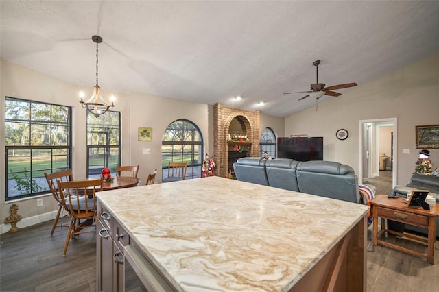 dining area featuring plenty of natural light, dark hardwood / wood-style floors, ceiling fan with notable chandelier, and vaulted ceiling