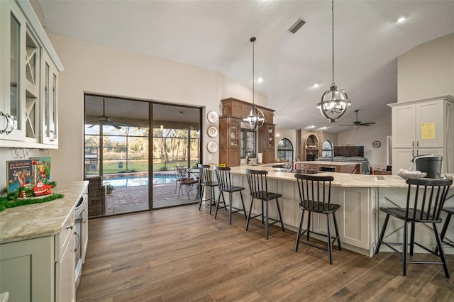 kitchen with pendant lighting, a kitchen breakfast bar, ceiling fan, and white cabinetry