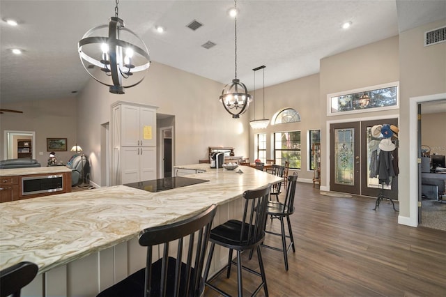 kitchen featuring a chandelier, decorative light fixtures, white cabinetry, and high vaulted ceiling