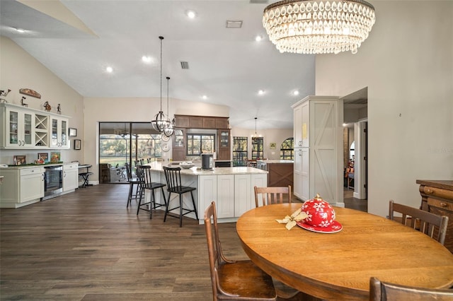 dining area with a notable chandelier, dark hardwood / wood-style floors, beverage cooler, and high vaulted ceiling