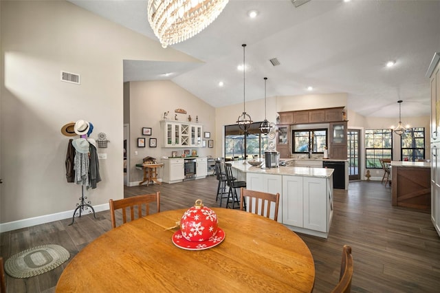 dining area with dark hardwood / wood-style floors, sink, high vaulted ceiling, and a chandelier